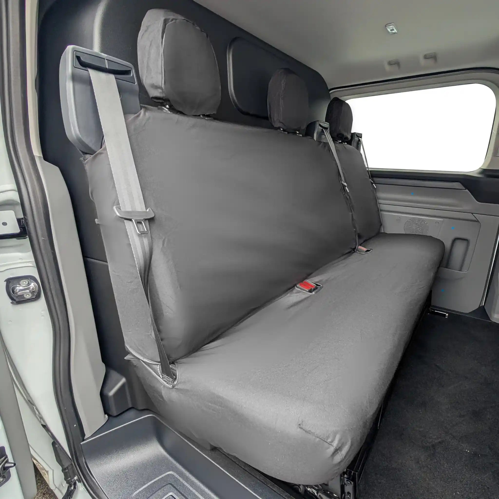 Black Ford Transit Custom rear seat cover on a vehicle's back seat with a visible brand logo
