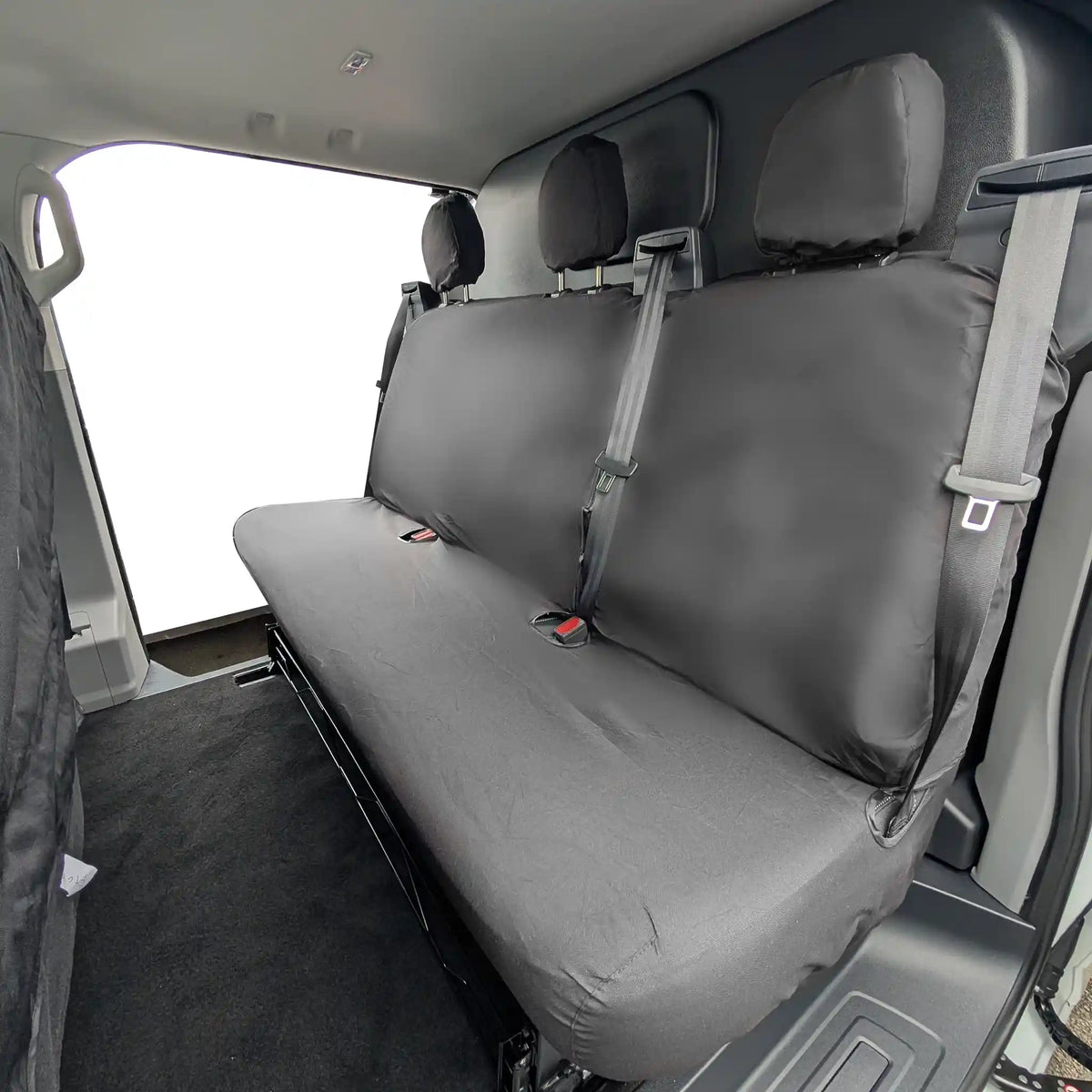 Black Ford Transit Custom rear bench seat cover in a vehicle with a clear view of the backseat.