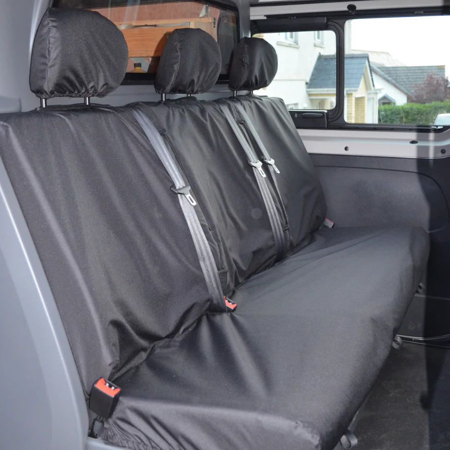 Black car seat covers on a vehicle's back seat with a view of the outside through the windows.