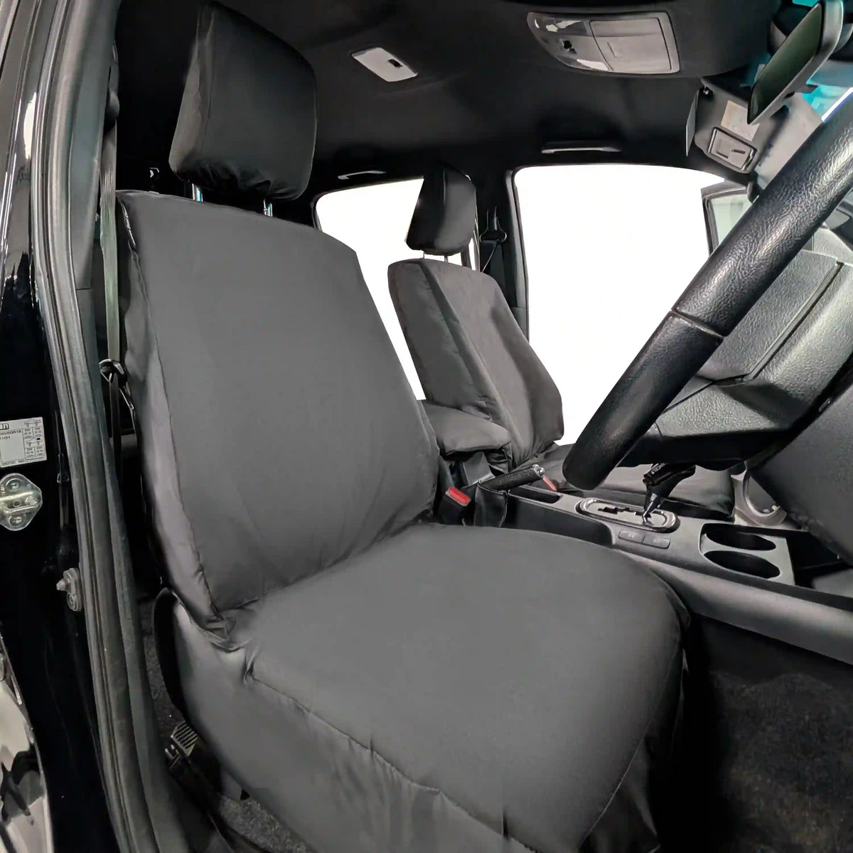 Black Toyota Hilux seat covers on a vehicle's front seats with a clear view of the dashboard.