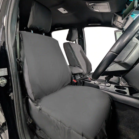 Black Toyota Hilux seat covers on a vehicle's front seats with a clear view of the dashboard.